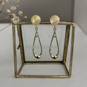 Lange slanke oorbellen van metaal aan een roomwitte RVS oorsteker