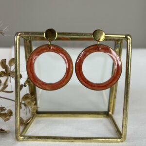 Ronde en strakke oorbellen met roestbruine resinhangers in een RVS gouden ring.