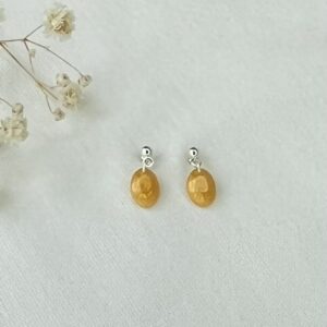 Mini ovale oorbellen van resin in een warme gele kleur met RVS zilveren oorknopjes