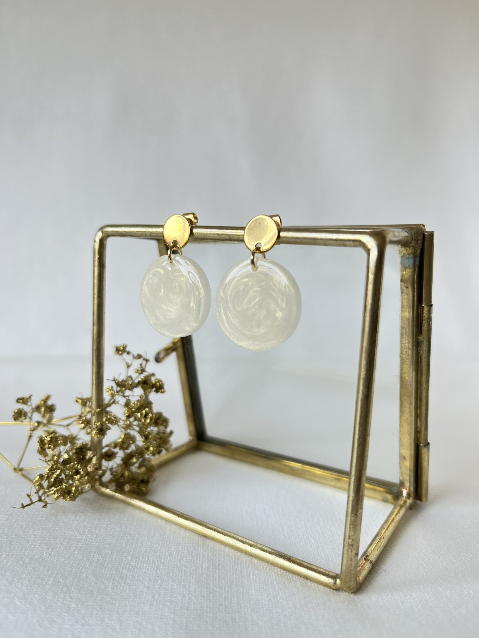 Ronde oorbellen van resin in een mooie parelmoer witte kleur met gouden glans