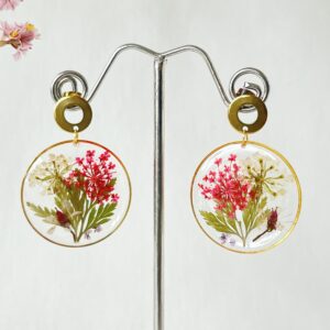 Ronde oorbellen van resin met een witte en roze droogbloem in een gouden RVS ring